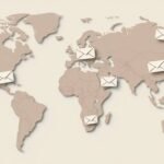 Imágen del mapa mundial en color plomo en un fondo rosado y simbolos de cartas en todos los paises